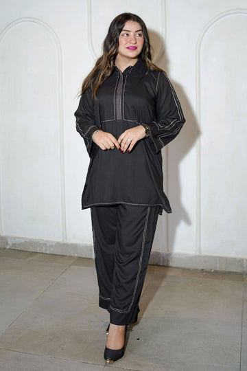 Woman wearing a black outfit against a white wall